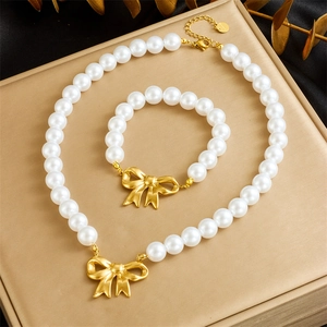 Close-up of pearl jewelry set featuring golden bow charms on beige velvet display
