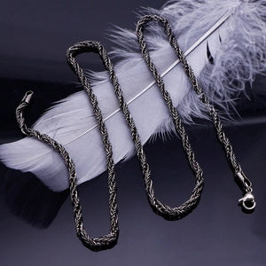 Detail of a thick gunmetal stainless steel rope chain necklace on a dark background