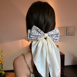 Floral print hair bow clip with long cream streamers and pearl accents on hair