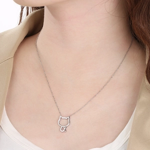 Gros plan d'un collier silhouette de chat évidé en argent porté au cou d'une femme