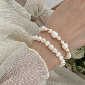 Close-up of elegant freshwater pearl bracelets with gold beads on a soft fabric background