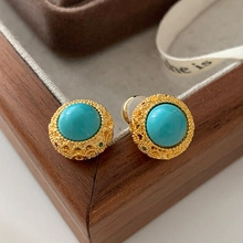 Detailed macro view of vintage gold stud earrings with round sky blue turquoise stones