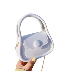 Mini white jelly bag with translucent finish and gold chain strap held in hand