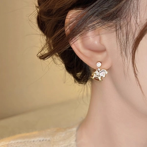 Detailed close-up of a gold-plated rocking horse earring with zircon and pearl on model