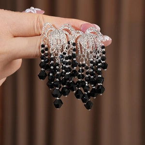 Detail of silver chain tassel earrings with layered black faceted glass beads