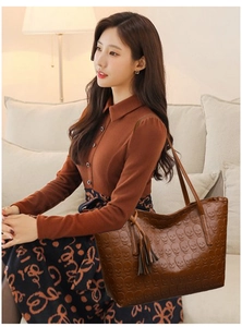 Detail of brown faux leather tote bag featuring skull embossing and tassel charm