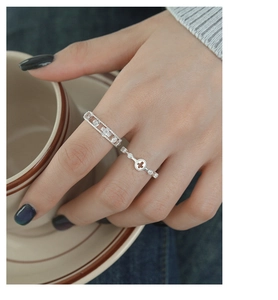 Detail of silver S925 rings with cross element and moving diamond on model hand