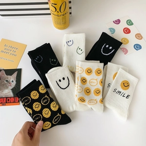 Detail of knit cotton mid-calf socks with yellow smiley faces and SMILE text