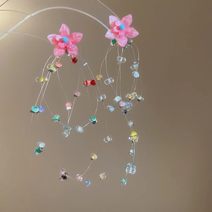 Close-up of pink flower stud earrings featuring colorful beaded tassels and silver pins