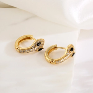 Macro detail of gold-plated snake hoop earrings with zircon and black gemstone eyes