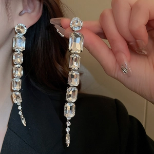 Detail of luxury long square earrings featuring dangling crystals on a metal base