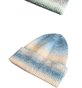 Detail of blue and orange tie-dye knit beanie showing thick texture and folded cuff
