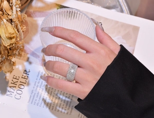 Close-up of wide pavé-set silver ring worn on hand with elegant lifestyle background accessories