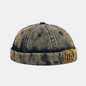 Detail of vintage acid wash denim docker hat with textured yellow fringe patch accent