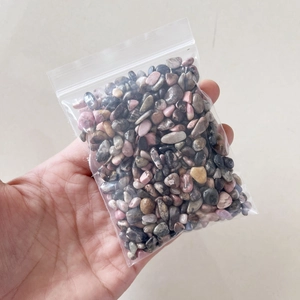 Detailed view of hand holding a bag of natural crushed crystal stones for healing