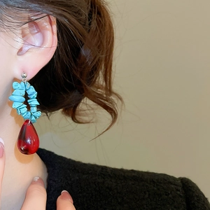 Detail of stone beaded drop earrings with blue pebbles and large red teardrop pendant