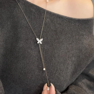 Detail of elegant butterfly pearl necklace with sparkling crystals worn on a dark sweater
