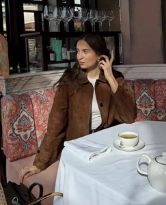 Detailed texture of brown suede jacket with lapel collar in a stylish outdoor setting