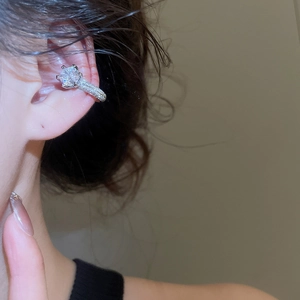 Close-up of a silver ear cuff with large round zircon in a classic six-prong setting