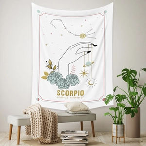 Detail of Scorpio zodiac tapestry with gold lettering and celestial patterns on white fabric