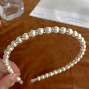 Elegant white pearl headband with gold metal ring and rhinestones on velvet background