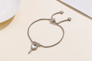 Détail du bracelet réglable avec clé en forme de cœur argentée et petits pendentifs