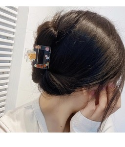 Acrylic claw clip with colorful Christmas motifs shown in dark hair updo hairstyle