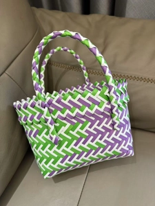 Close-up of handmade woven tote bag showing purple and green checkered texture on a sofa