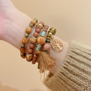 Detail of bohemian multilayer sandalwood beaded bracelet with tree of life charm and tassel