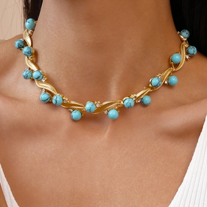 Close-up of golden necklace featuring textured blue turquoise beads and sparkling crystals