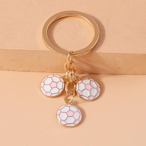 Detail of gold keychain featuring three pink and white soccer ball charms on link chains