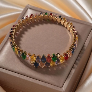 Detail of a gold bracelet with colorful oval gemstones displayed on a silk background