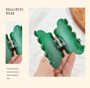 Macro detail of a medium green acrylic hair claw clip with shimmering glitter finish