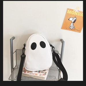 Detail view of white ghost crossbody bag with black eye patches and nylon shoulder strap