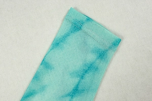 Detail of teal tie-dye mesh fabric with precision double-needle stitching on long dress