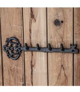 Vintage cast iron key-shaped wall hook with four hooks on a natural wooden background