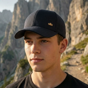 Outdoor stylish men's black baseball cap with golden metallic logo on a mountain path