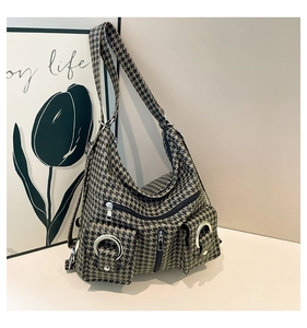 Close-up of houndstooth shoulder bag showing dual front pockets and metal ring details