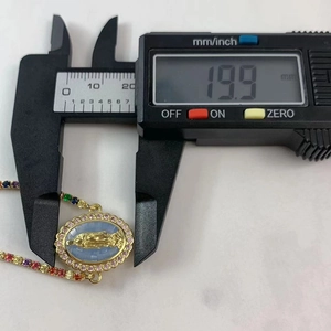 Macro shot measuring Virgin Mary pendant width at 19.9mm with pink gemstones