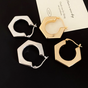 Detailed view of polished geometric hexagonal hoop earrings in gold and silver finish