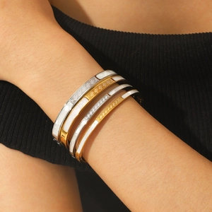 Set di quattro bracciali in acciaio oro e argento con intarsio bianco e motivo greco