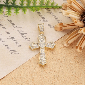 Macro detail of gold-plated cross pendant with micro-pave zircons and heart center