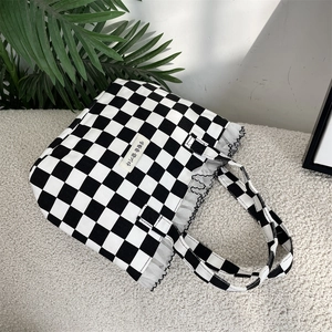 Close-up of black and white checkered canvas tote bag with lace trim and Korean text label