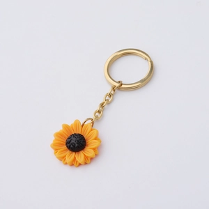 Detailed close-up of polished golden keychain with a vibrant yellow sunflower pendant