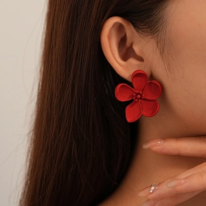 Vintage matte red flower stud earrings with five petals and fine pistils worn by model