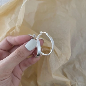 Minimalist S925 sterling silver hoop earrings with smooth polished finish held in hand
