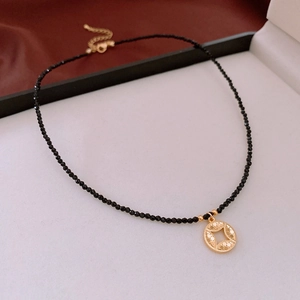 Close-up of black faceted crystal bead necklace with round golden filigree pendant