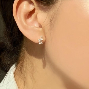 Detailed close-up of a silver geometric earring featuring clear zircon stones on a model