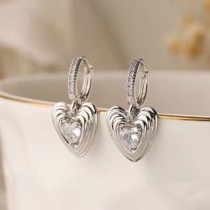 Créoles en argent avec pendentifs coeur en zircon sur le bord d'un bol en porcelaine