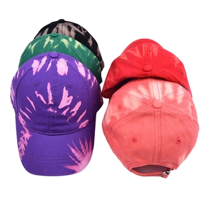 Detail view of adjustable metal buckle strap on various tie-dye baseball caps